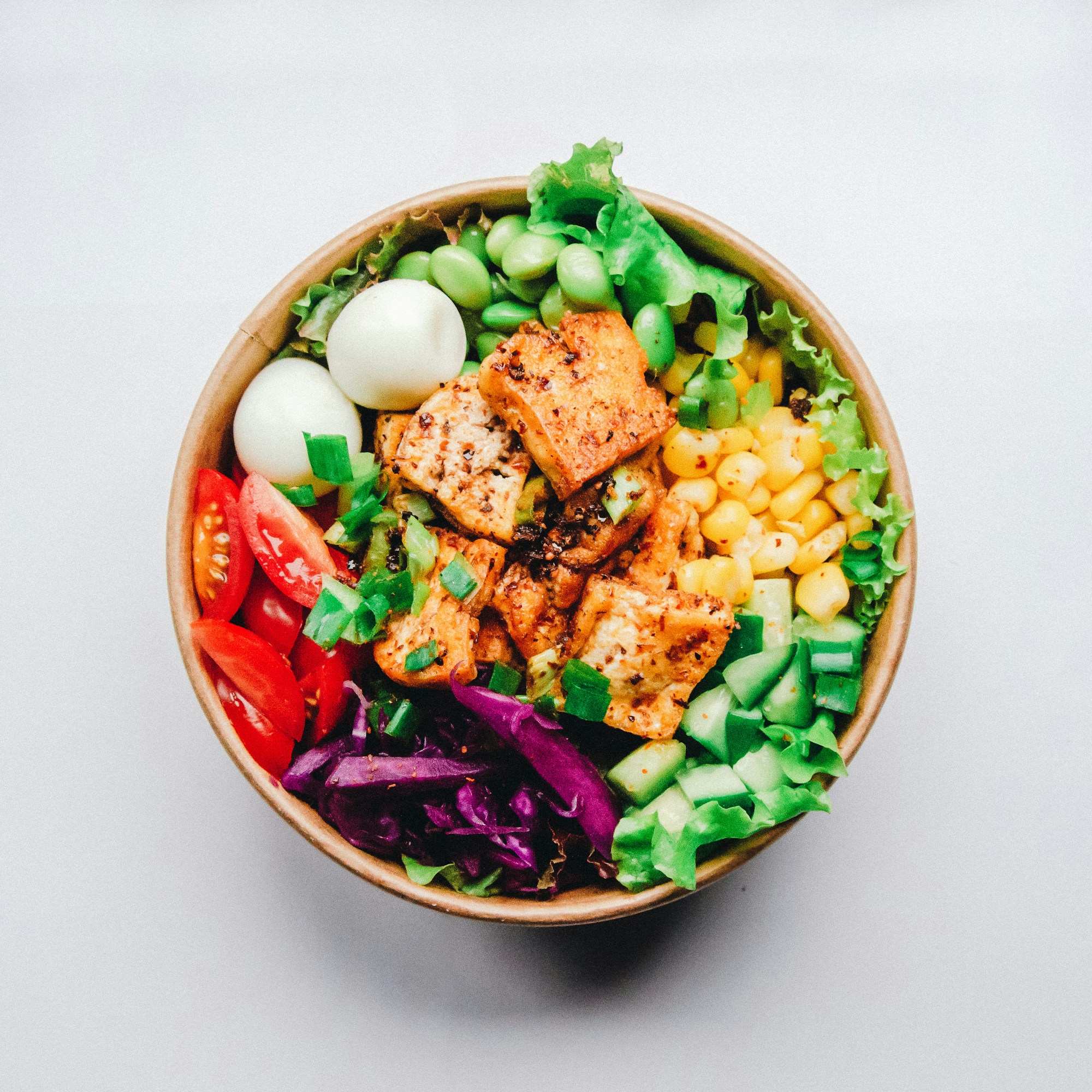 A colourful grain bowl with grilled tofu, vegetables and greens.
