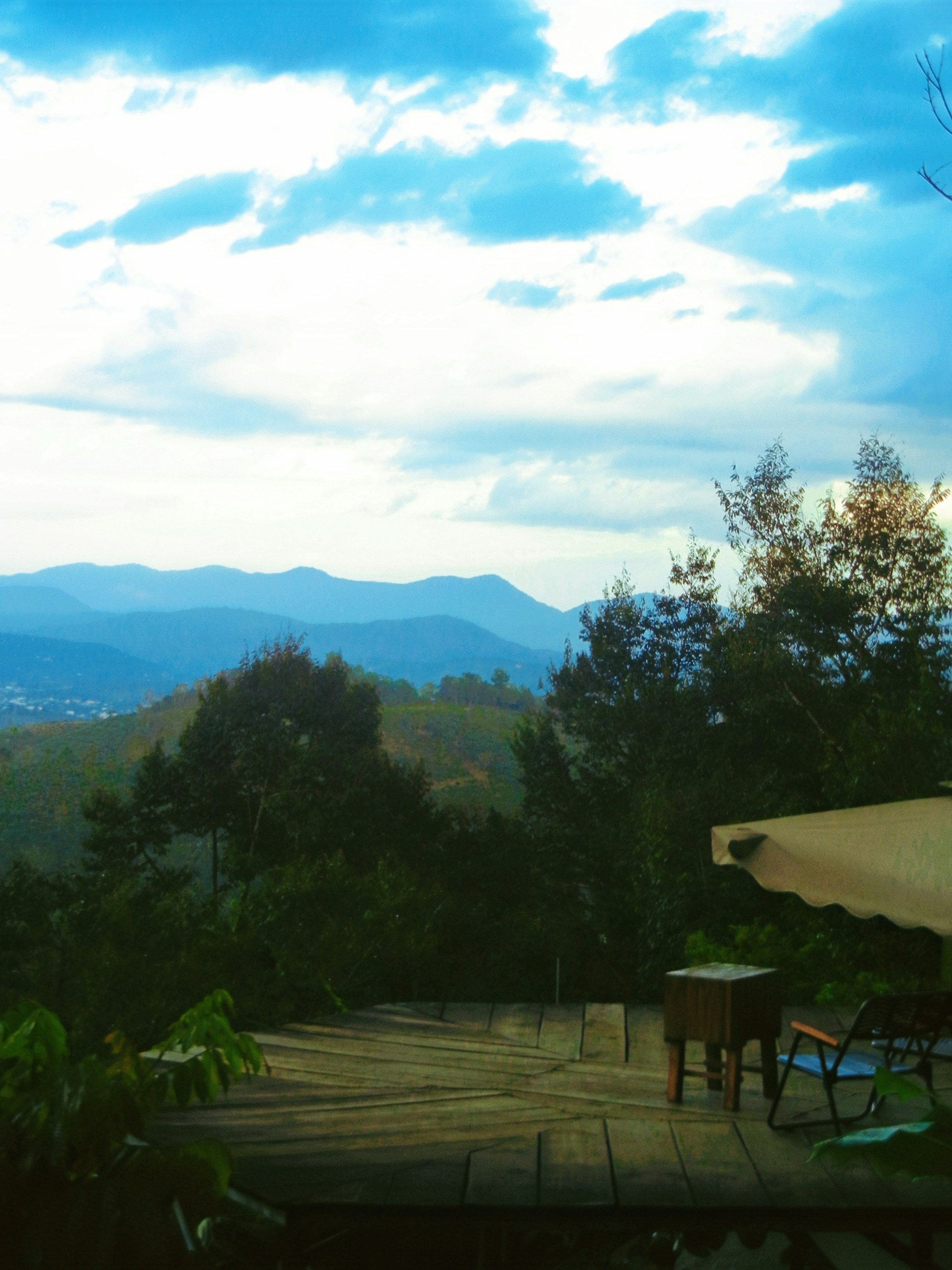 A wooden deck opening onto hills and open sky.